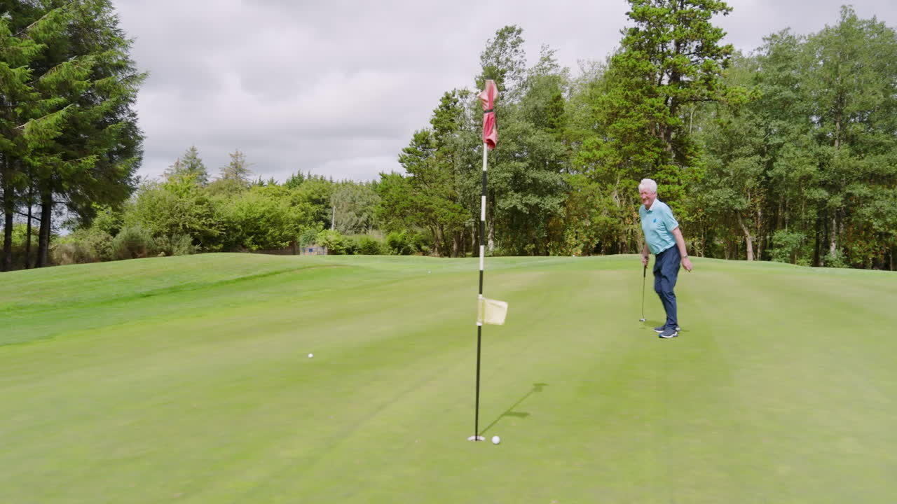 Golf players playing golf and knocking golf ball into cup on golf course on cloudy day