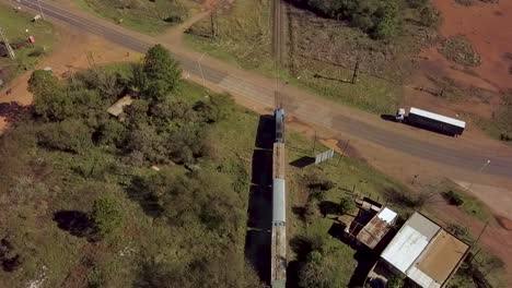 Un-Largo-Tren-Que-Pasa-Por-Una-Zona-Rural-En-Argentina,-Movimiento-Lento,-Vista-Aérea