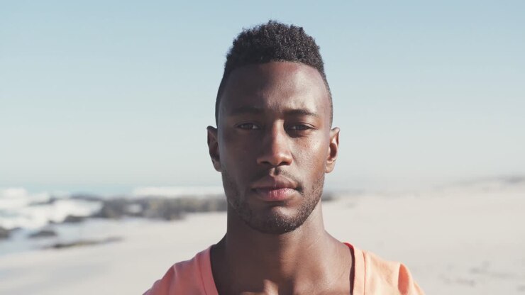 African American man looking and smiling at camera seaside