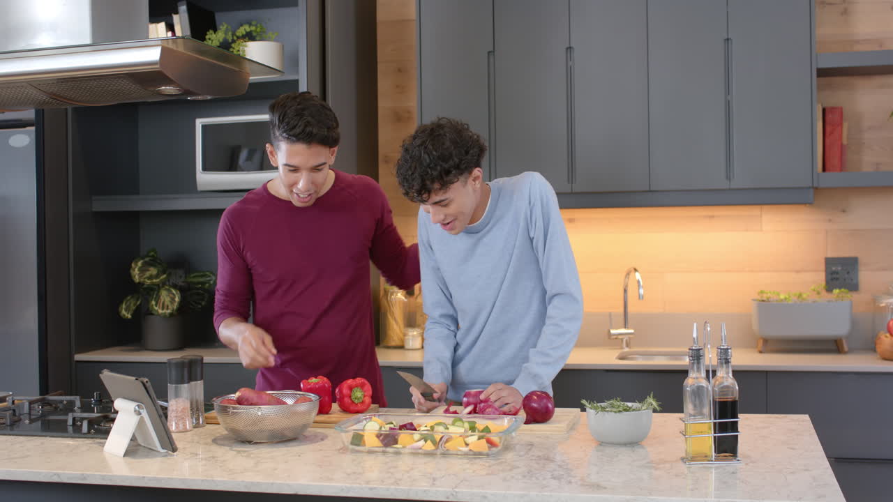 Preparing meal, multiracial gay couple chopping vegetables together in modern kitchen, at home