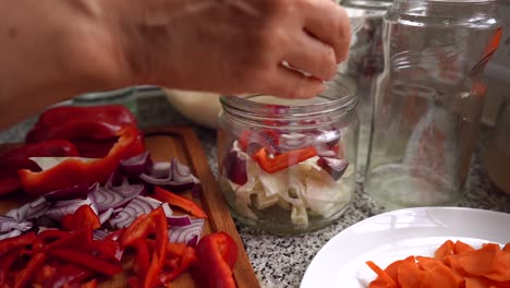 adding chopped red onions in a glass jar