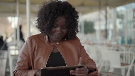 smiling young woman using digital tablet in cafe