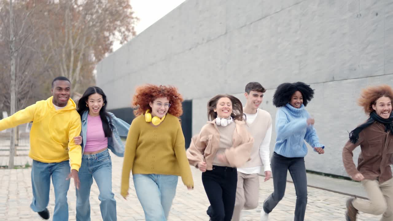 Multi-ethnic playful and happy friends running together outdoors