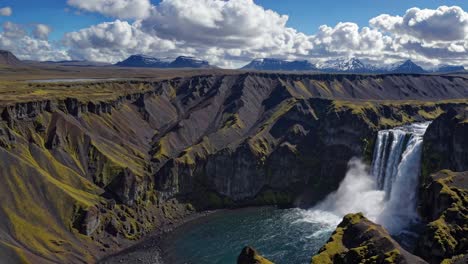 Aerial video of a majestic waterfall cascading into a canyon, surrounded by rugged cliffs