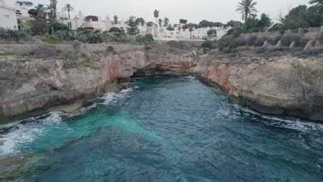 Luftaufnahmen-Mit-Rückwärts--Und-Hochkippbewegung-Auf-Einer-Wunderschönen-Und-Unberührten-Badekappe-Mit-Blick-Auf-Kleine-Weiße-Luxusunterkünfte-In-Palma-De-Mallorca,-Spanien