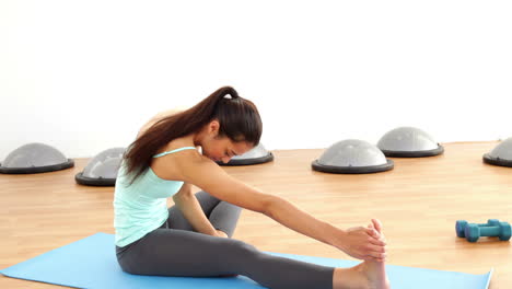 fit brunette stretching on exercise mat