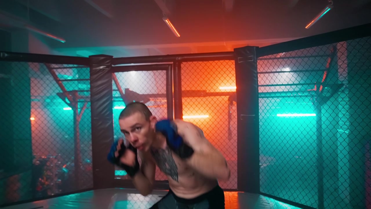Ung mand skyggebokser i et MMA-bur med neonlys.