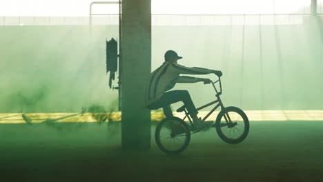 bmx rider in an empty warehouse using smoke grenade