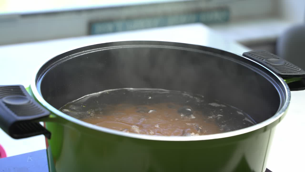 Steaming pot of boiling water on the stove, cooking spaghetti in home kitchen, close up