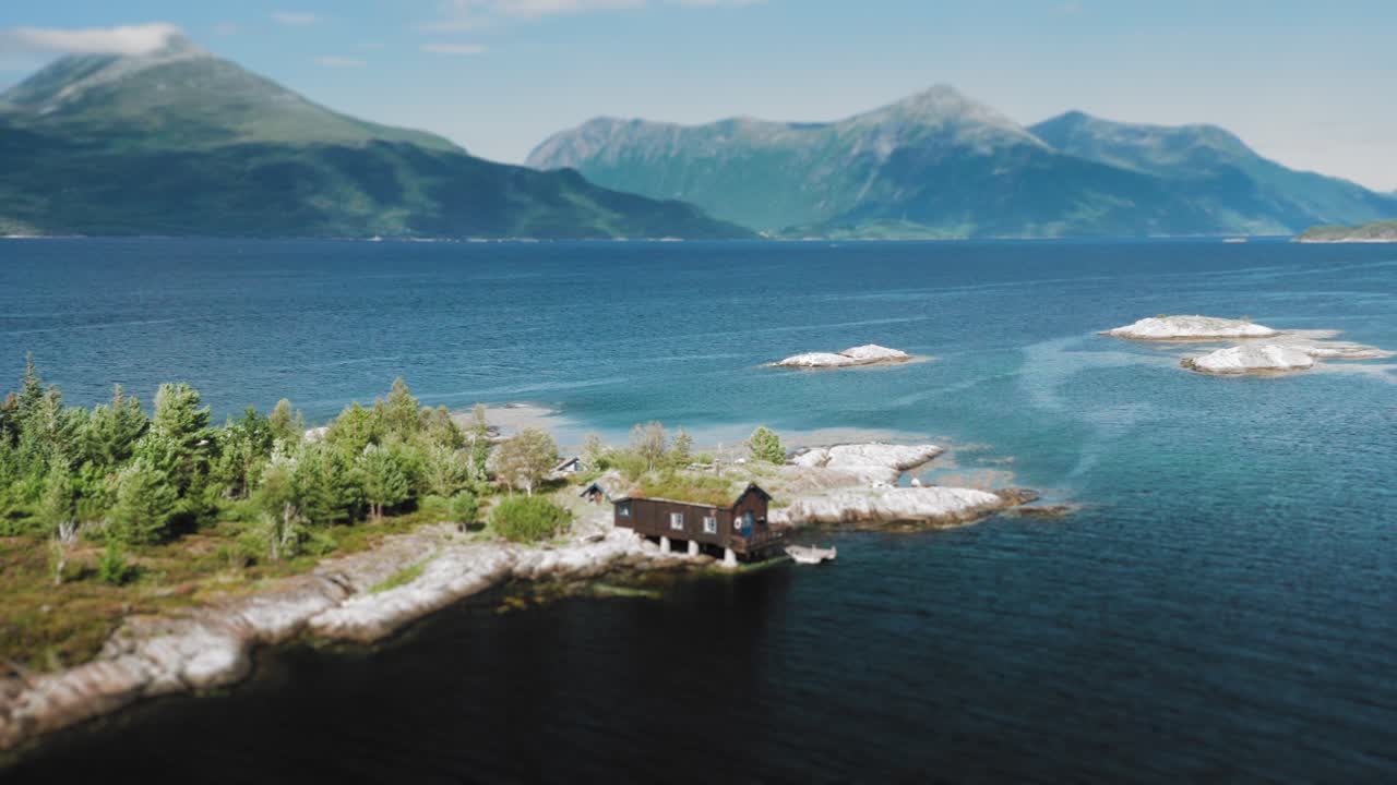 una vista aérea de una pequeña casa con techo de césped que se encuentra en la orilla de una isla
