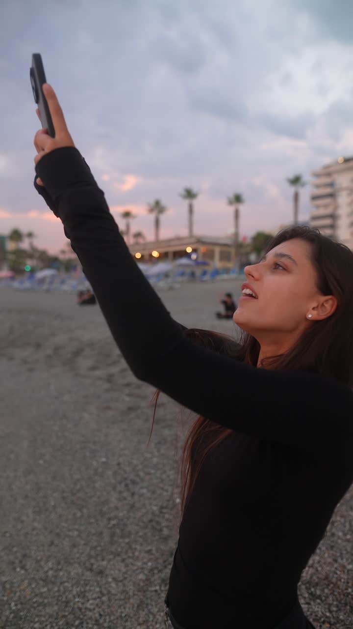 mujer tomando una foto de una puesta de sol en la playa