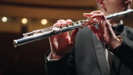 flutist is playing in symphonic orchestra or brass band closeup view of flute in male hands