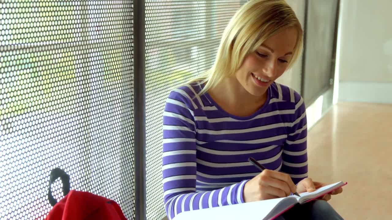 Glad student som skriver vid fönstret