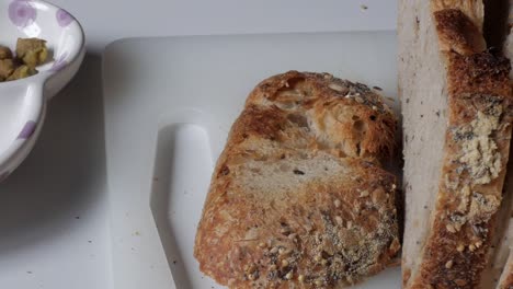 crusty olive bread with green olives and nuts on a white cutting board
