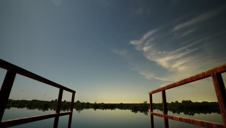 night time lapse of stars turning into sunrise from dock overlooking texas lake in summertime