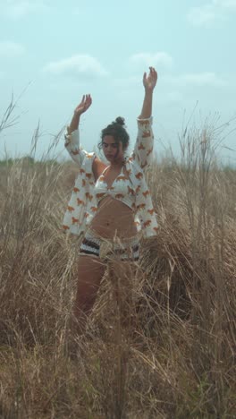 young woman dancing in nature, enjoying freedom and movement in grassy field