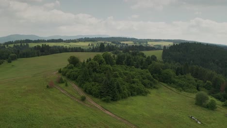 Aerial-view-of-a-countryside-with-mountains,-forests-and-meadows