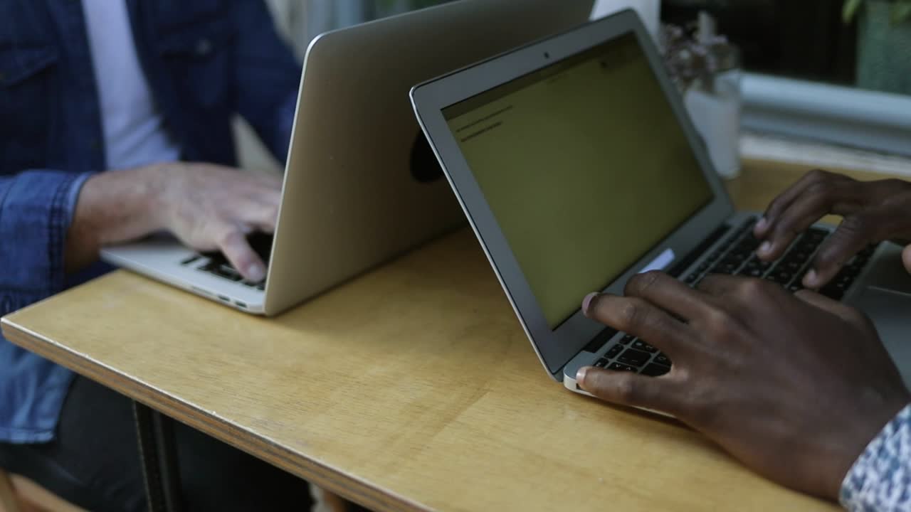 Multiethnic men working with laptops in cafe