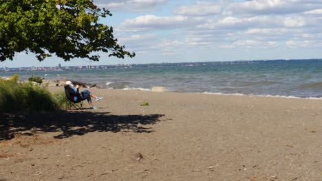 un momento relajante de leer un libro en la playa frente a las olas ondulantes, con una ciudad visible en la lejana costa