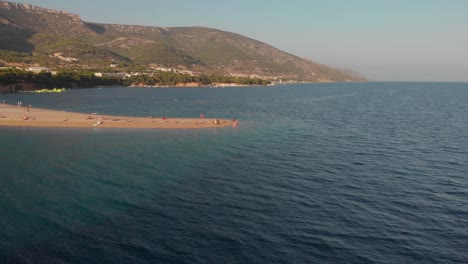 Volando-Lentamente-Hacia-El-Final-De-La-Famosa-Playa-De-Zlatni-Rat-En-La-Isla-De-Brac-En-Croacia,-Revelando-Turistas-Y-Bañistas