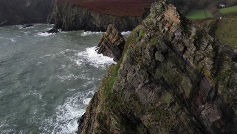 nohoval cove, ireland, cinematic aerial view of scenic coastline rocks and waves on sunny day, revealing drone shot