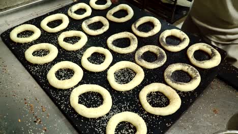 baker sprinkles bagels with sesame and poppy seeds