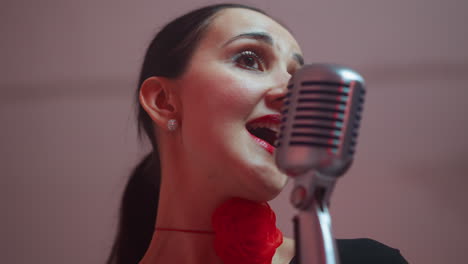 close-up of a joyful female vocalist with red lips and a ribbon around her neck singing passionately into a vintage microphone, capturing her expressive performance and vibrant energy