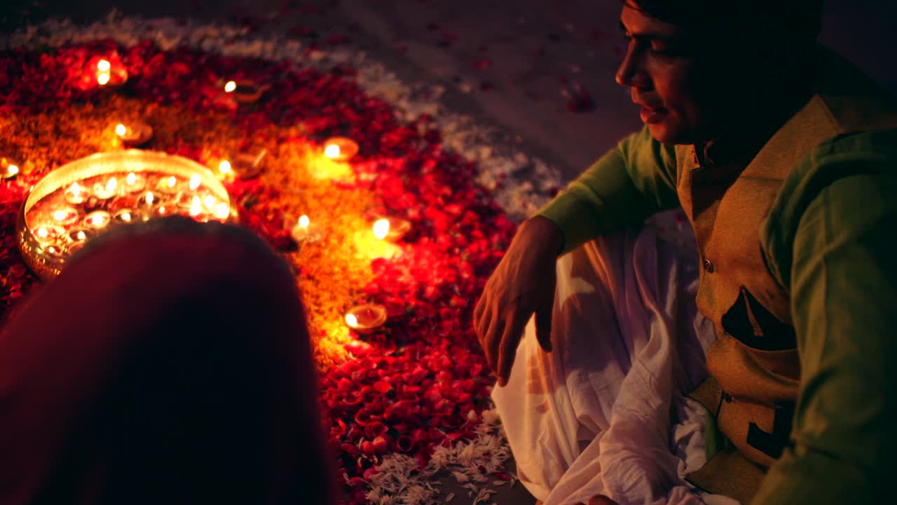 Couple celebrate a colorful Diwali rangoli- red pink orange green