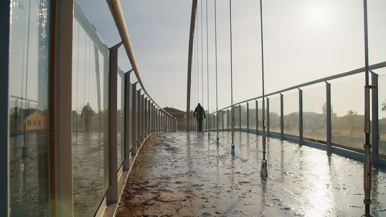 vista trasera de hombres irreconocibles caminando por el puente peatonal al amanecer