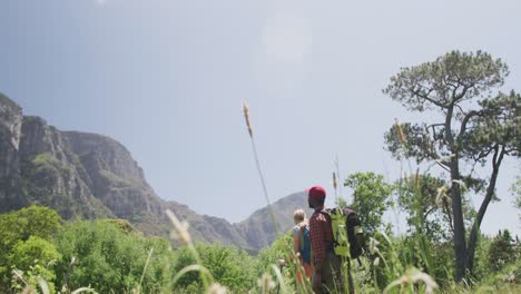 pareja diversa caminando con mochilas y palos de senderismo en las montañas, cámara lenta