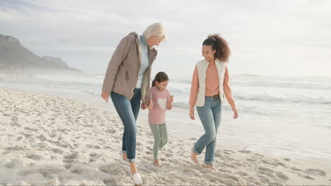 mother, grandma and girl holding hands at beach