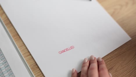 a hand stamps 'cancelled' on a document