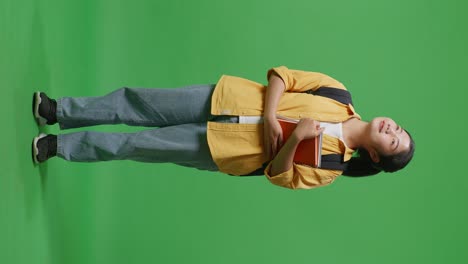 student holding books on green screen