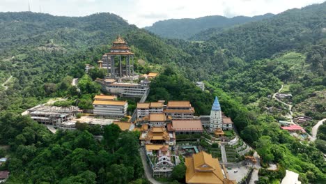 kek lok si temple with lush greenery and mountainous backdrop in penang, aerial view
