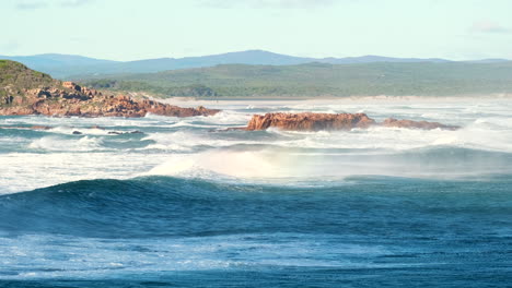 wind blows sea spray backwards over crashing waves, slow motion