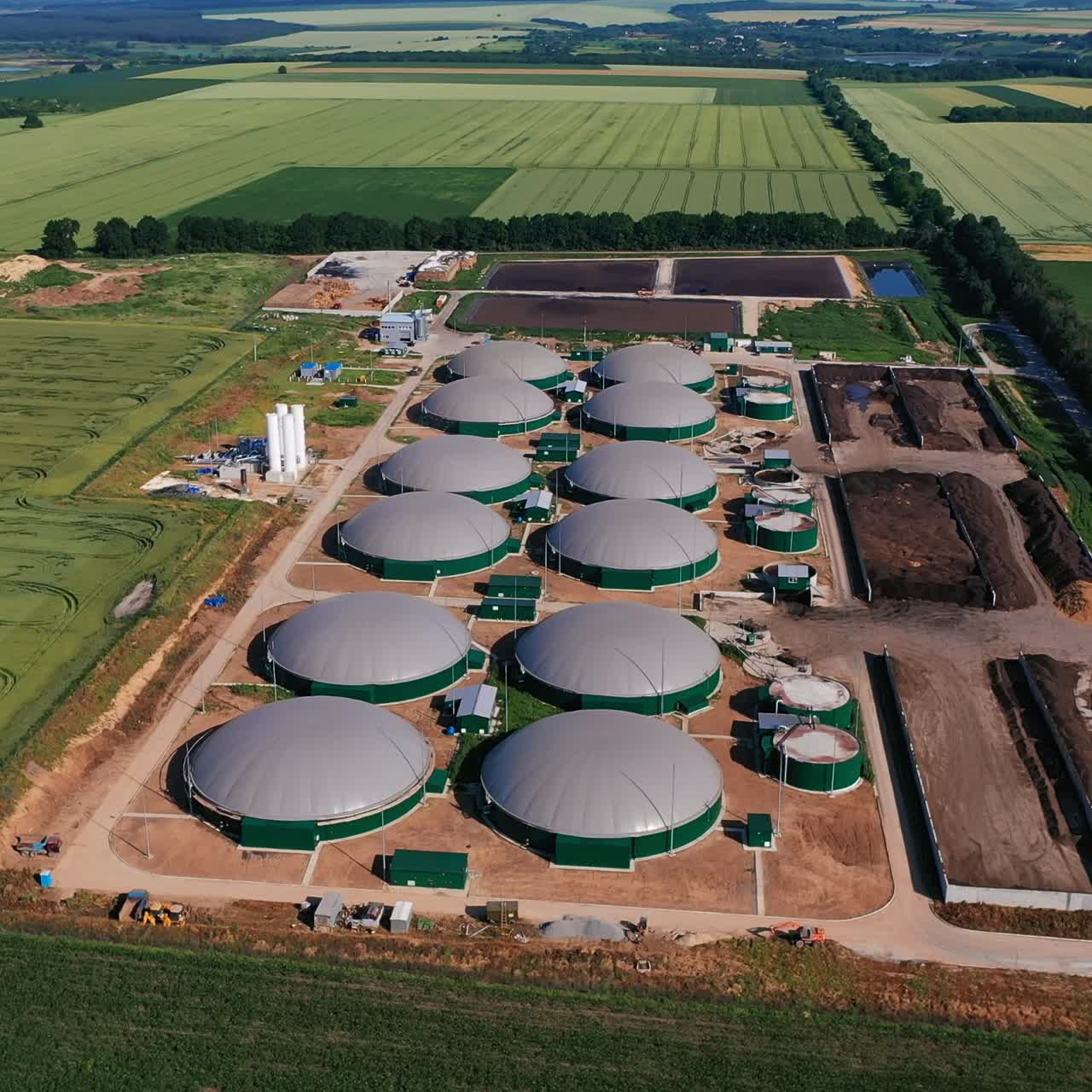 Organic plant for environmentally friendly fuel production. Big biogas factory among the field. Aerial perspective