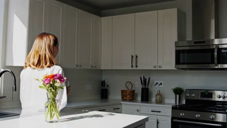 mujer bebiendo agua en una cocina moderna
