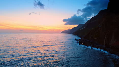 the atlantic ocean at the rocky coast of the madeira islands, portugal. drone footage above the waterscape at sunset time.