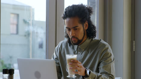 ejecutivo tomando café mientras usa una computadora portátil 4k