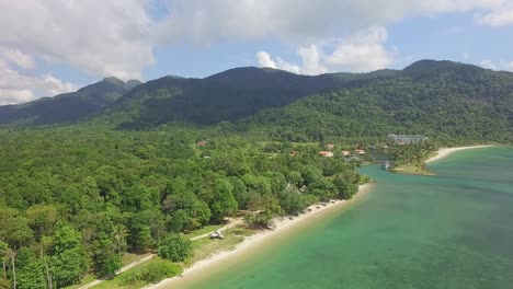 Aerial-side-dolly-shot-of-a-topical-beach-on-Koh-Chang-with-resorts-on-the-beach-and-lush-dense-Jungle-and-mountains-and-ocean