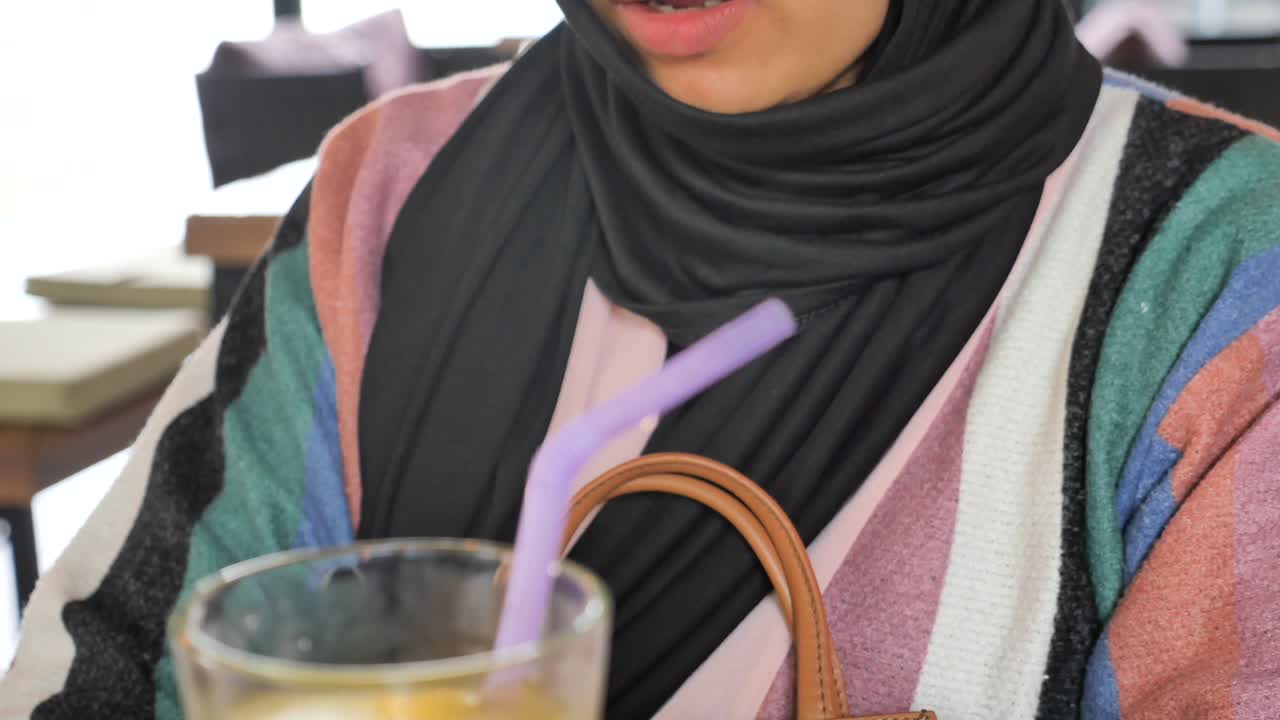 una mujer bebiendo jugo en un café.