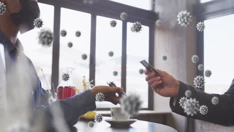 Animation-of-virus-cells-over-african-american-woman-paying-with-smartphone