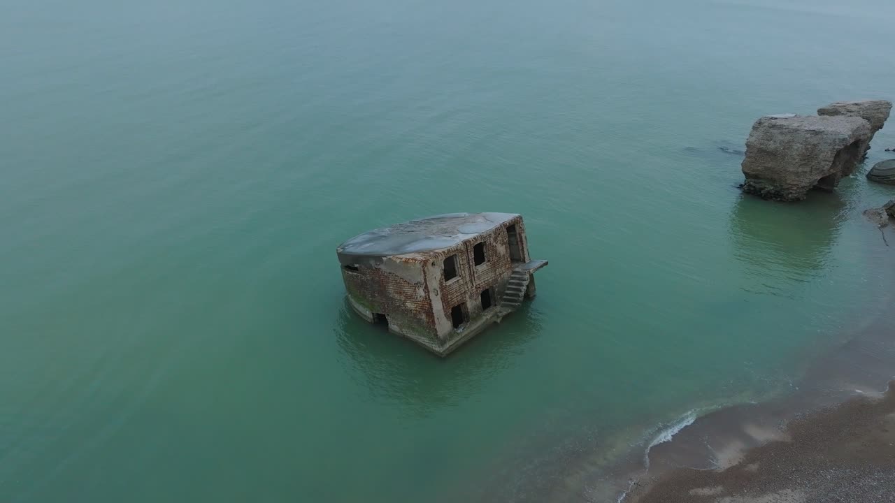 вид с высоты птичьего полета на заброшенные приморские фортификационные сооружения в северных фортах кароста на берегу балтийского моря, пасмурный день, широкая съемка с дрона, движущегося вперед, наклон камеры вниз