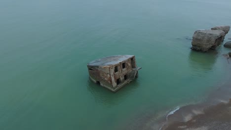 aerial birdseye view of abandoned seaside fortification building at karosta northern forts on the beach of baltic sea , overcast day, wide drone shot moving forward, camera tilt down