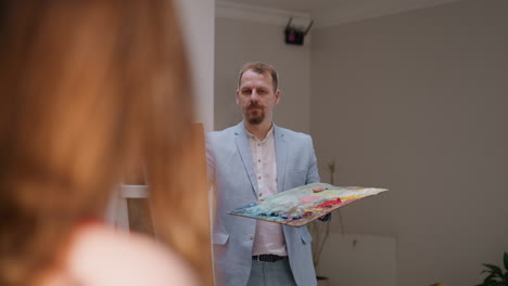 artist with piercing eyes draws life in studio. elegant painter creates woman portrait working with model in workshop. creative occupation and hobby