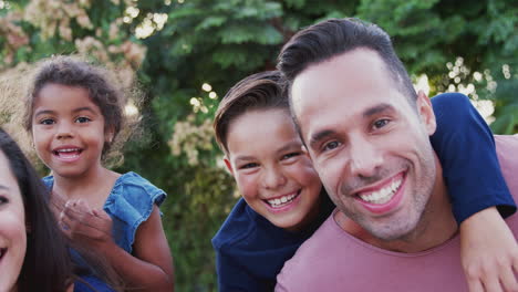 retrato de una familia hispana sonriente con padres que dan paseos a los niños en el jardín en casa