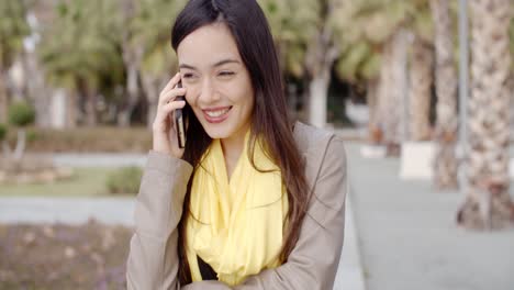 Mujer-Joven-De-Pie-Hablando-Por-Su-Teléfono-Móvil