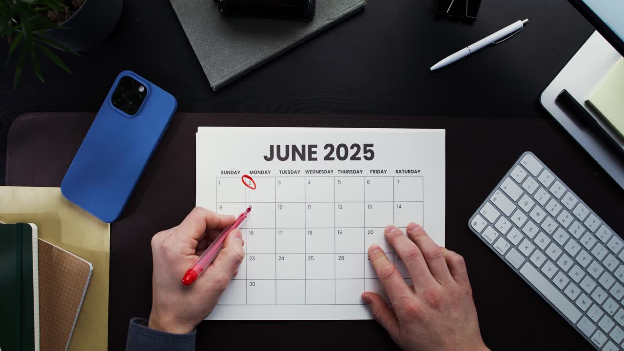 Person marking dates on a June 2025 calendar