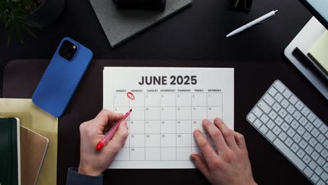 person marking dates on a june 2025 calendar