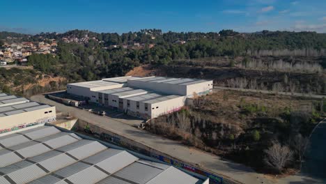 industrial warehouses near wooded area in abrera, barcelona, spain, under clear skies, aerial view